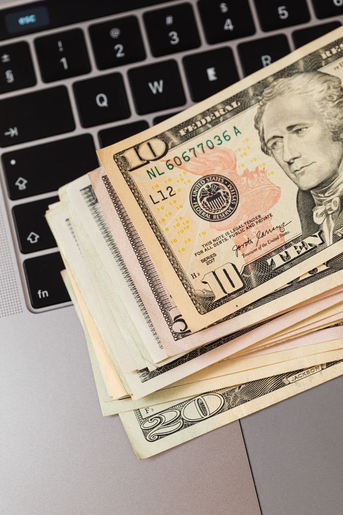 About Close-up of US dollar bills stacked on a laptop keyboard, representing online finance.